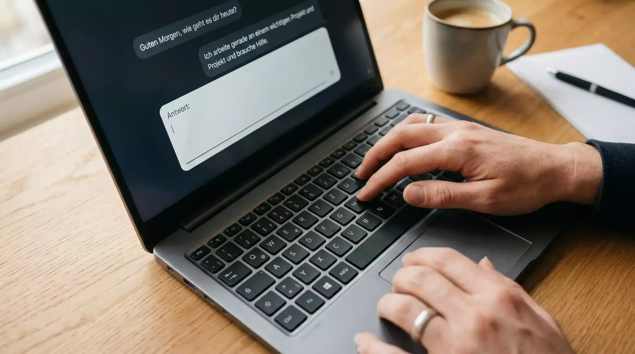 Hände tippen auf Laptop-Tastatur mit ChatGPT-Oberfläche im Hintergrund